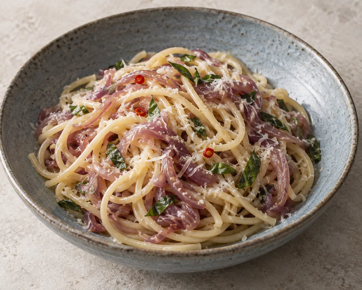 Spaghetti with soft purple-pink Tropea onion strands, small pieces of red chile, basil, and grated pecorino.
